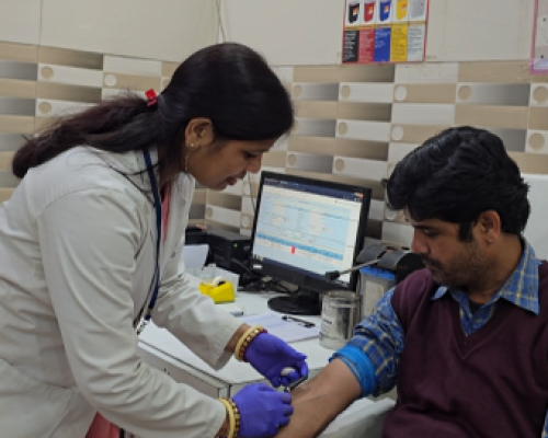 Phlebotomist collecting a blood sample from a patient during home sample collection service by a pathology lab in Udaipur.